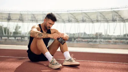 Runner sitting and takes supplement after running